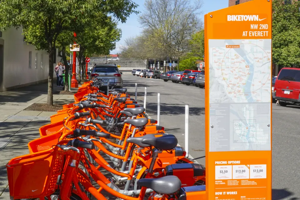 Numerous orange Portland Biketown bikes are parked at a facility in Northwest Oregon.